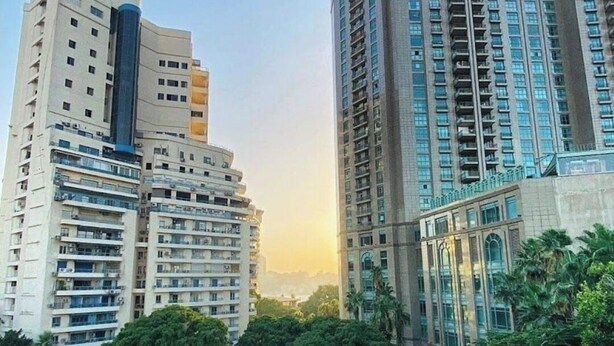 A high-rise building with multiple floors, large windows, and a modern architectural design. - Quiet Spacious Room.. Garden City, 2 Min to Nile (Cairo Governorate)