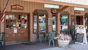 A storefront with signs for 'Book Peddler' and 'Espresso Bar', featuring a rustic wooden facade, outdoor seating with chairs, and a flower arrangement. - Escape to The Adventure Inn Yellowstone- Absaroka, just a minute from the park! (West Yellowstone)