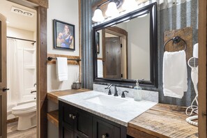 Une salle de bain dotée d’un grand miroir, de deux lavabos, d’un meuble-lavabo en bois et d’un porte-serviettes.