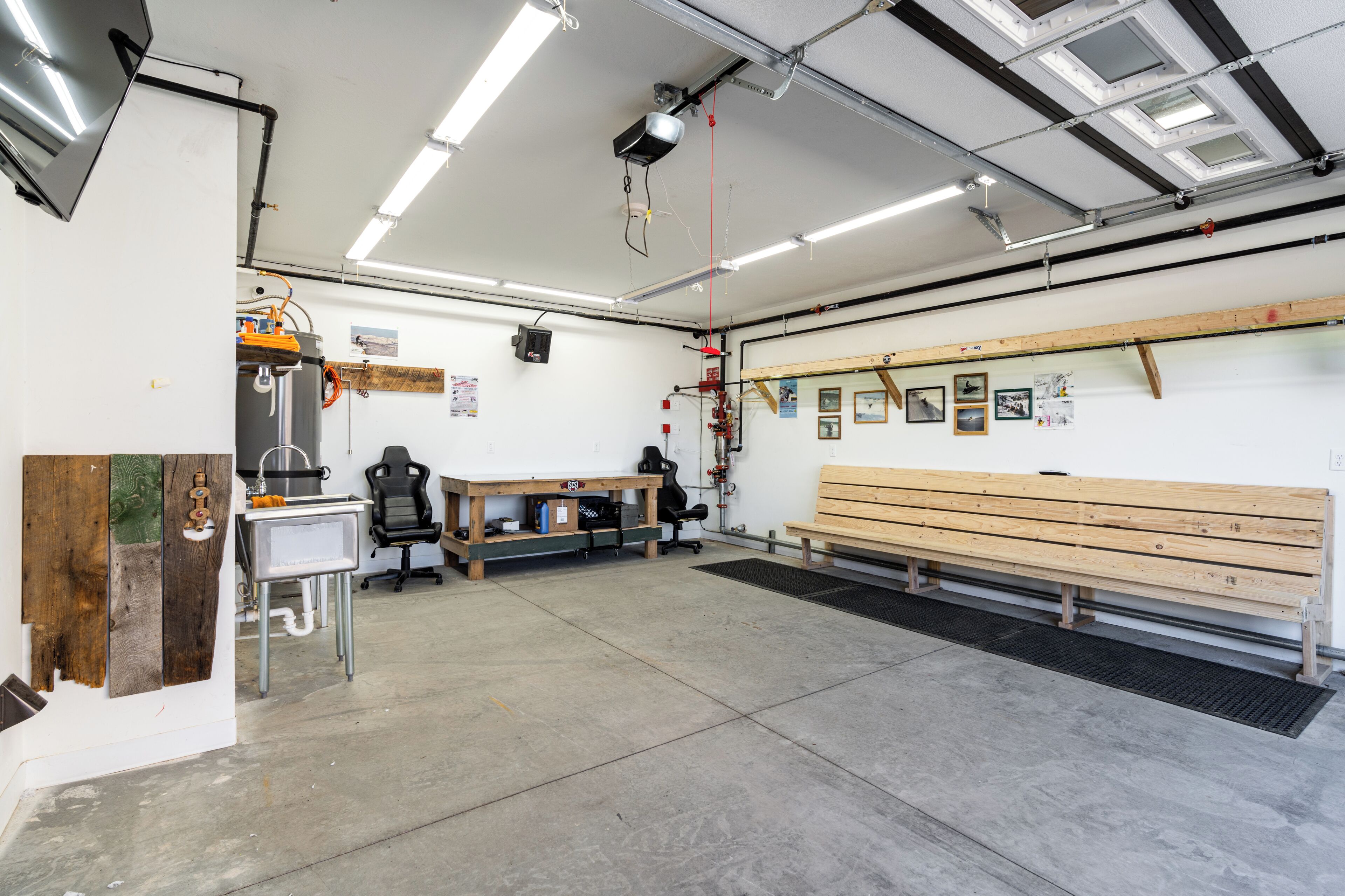 A spacious indoor area with a wooden bench, a desk with a chair, and a projector mounted on the ceiling.