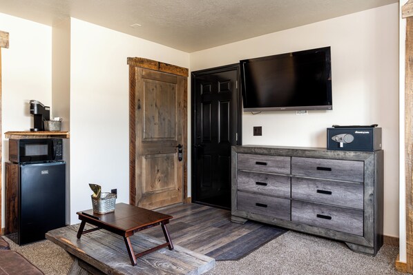 A compact living space with a kitchenette, a flat-screen TV, and a wooden door.