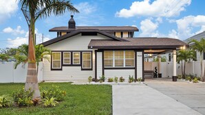 A single-story house with a sloped roof, a front porch, and a small garden with various plants. - Habana Luxury Bungalow- Heated pool (Tampa)