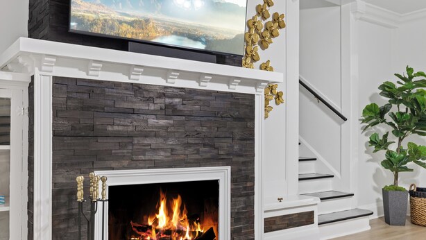 A fireplace with a modern design, a staircase, and a television mounted above it. - Habana Luxury Bungalow- Heated pool (Tampa)