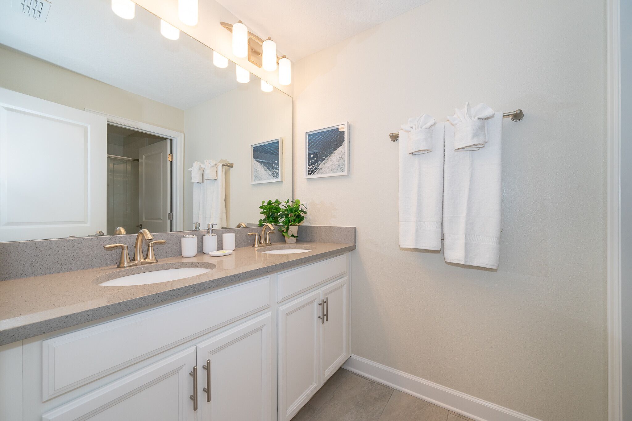 A bathroom with a double sink vanity, a large mirror, and two towels hanging on a towel rack.