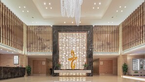 A spacious lobby with a central reception desk, a decorative wall with a geometric pattern, and a modern chandelier. - Best Boutique Hotel (Shanghai)