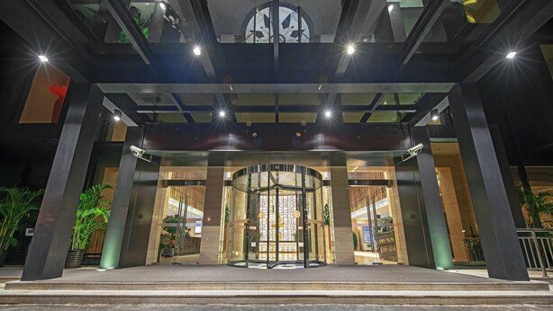 A modern hotel entrance with a revolving door, large glass windows, and a central light fixture. - Best Boutique Hotel (Shanghai)