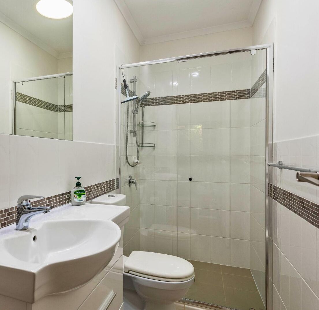 A compact bathroom with a glass-enclosed shower, a white sink, and a toilet.