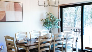 A dining area with a wooden table, white chairs, and a vase with green foliage.