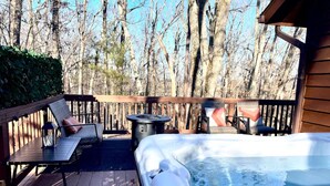 A wooden deck with a hot tub, lounge chairs, and a table.