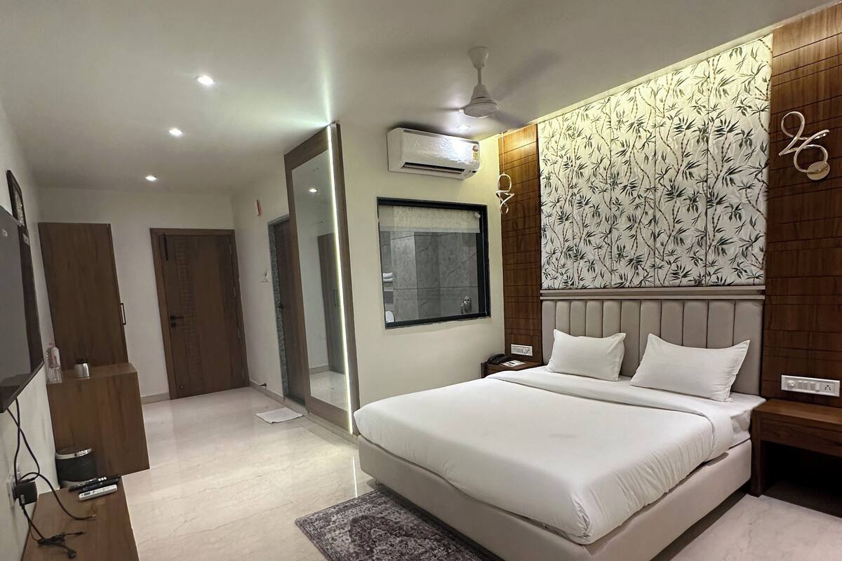 A modern bedroom with a large bed, a wooden headboard, a patterned wallpaper, and a ceiling fan.