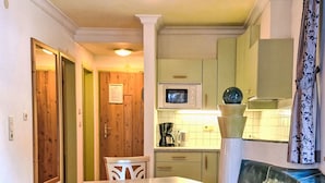 A compact kitchen with a dining table, a microwave, and a coffee maker.