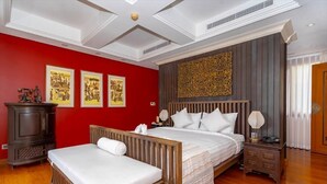 Une chambre d’hôtel avec un grand lit, un plus petit lit, un banc en bois, une table de chevet et un panneau décoratif mural.
