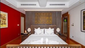 Une chambre d’hôtel avec un grand lit, deux tables de chevet, un panneau décoratif au mur et un mur d’accent de couleur rouge.