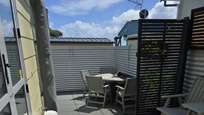 A patio area with a wooden deck, a white outdoor seating area, and a small table with chairs.