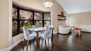 Un coin repas avec une table et des chaises en verre, un canapé blanc et un plancher en bois.