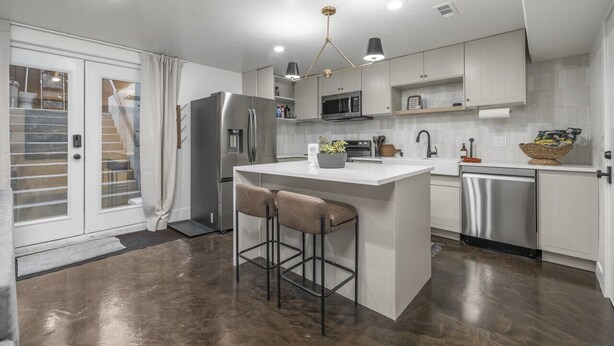Una cocina moderna con una isla central, electrodomésticos de acero inoxidable y vistas al exterior.