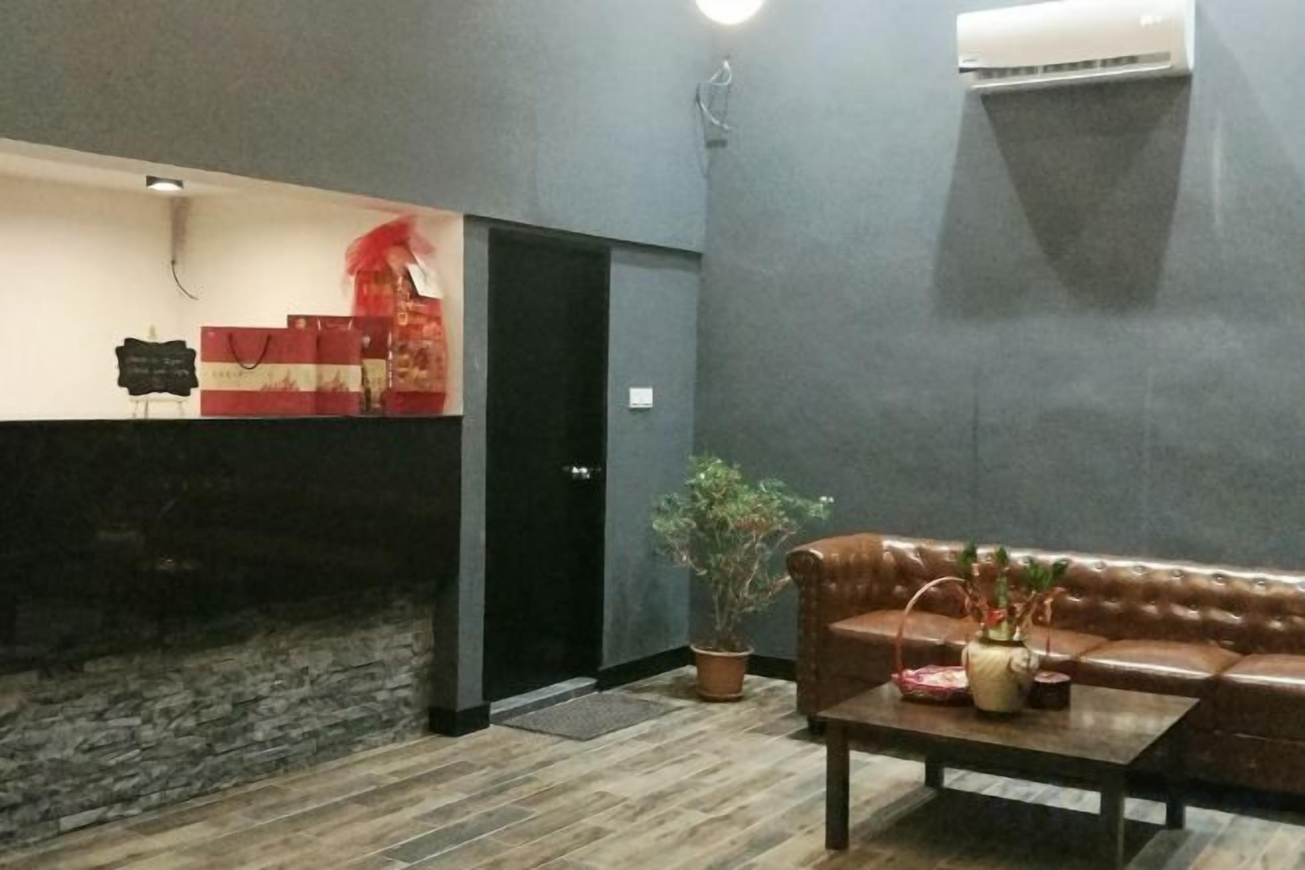 A reception area with a reception desk, a black door, a potted plant, a leather sofa, and a coffee table.