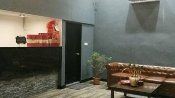 A reception area with a reception desk, a black door, a potted plant, a leather sofa, and a coffee table.