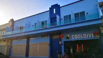 A two-story building with a blue facade, a visible storefront with signage, and a garage door.