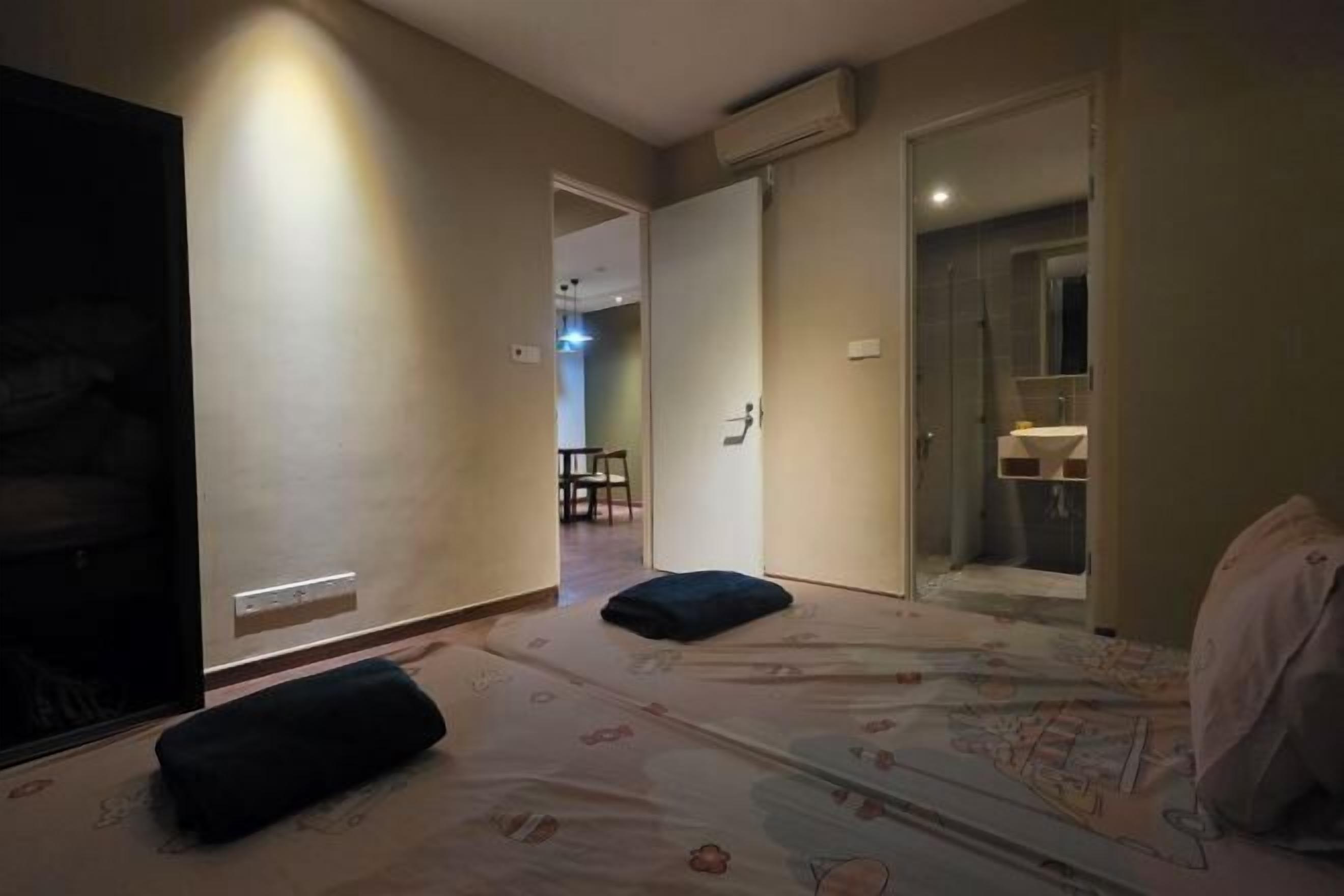 A hotel room with a bed, a bedside table, a chair, and a bathroom visible through an open door.