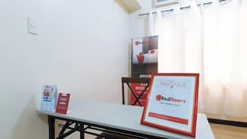 Una habitación de hotel con una mesa, un certificado enmarco y un cartel en la pared.