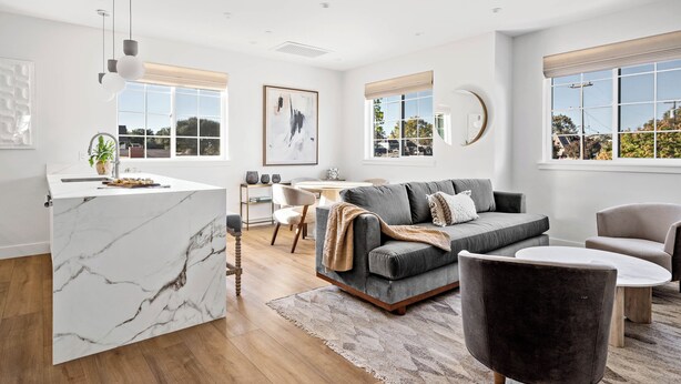 A modern living room with a marble island, grey sofa, and a dining area with a round table. - 2 bedroom - WiFi, AC, garaged off-street parking with EV Charger. (Solvang)