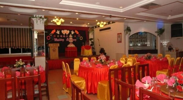 A banquet hall with round tables, red and gold chairs, and a stage with a backdrop. - Li Hua Hotel Bintulu (Bintulu)