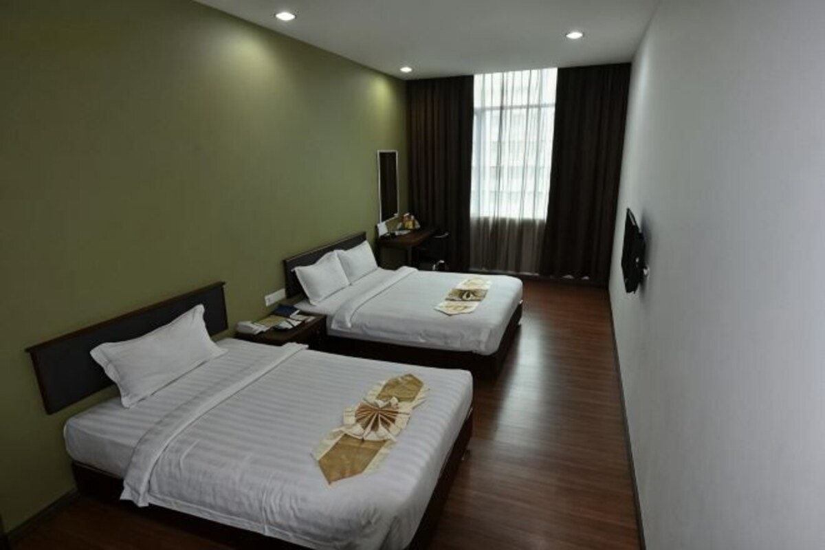 Habitación de hotel con dos camas, una mesita de noche, un espejo y una ventana con cortinas.