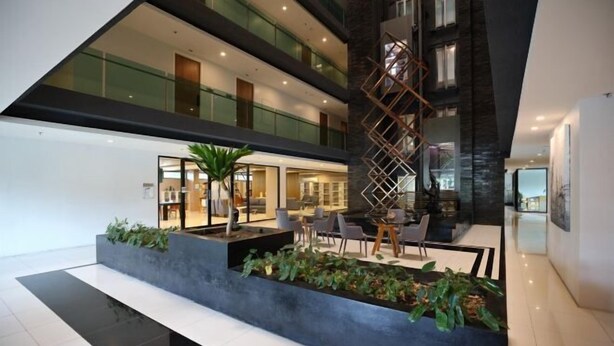A modern hotel lobby with a central seating area, a staircase, and a glass railing.