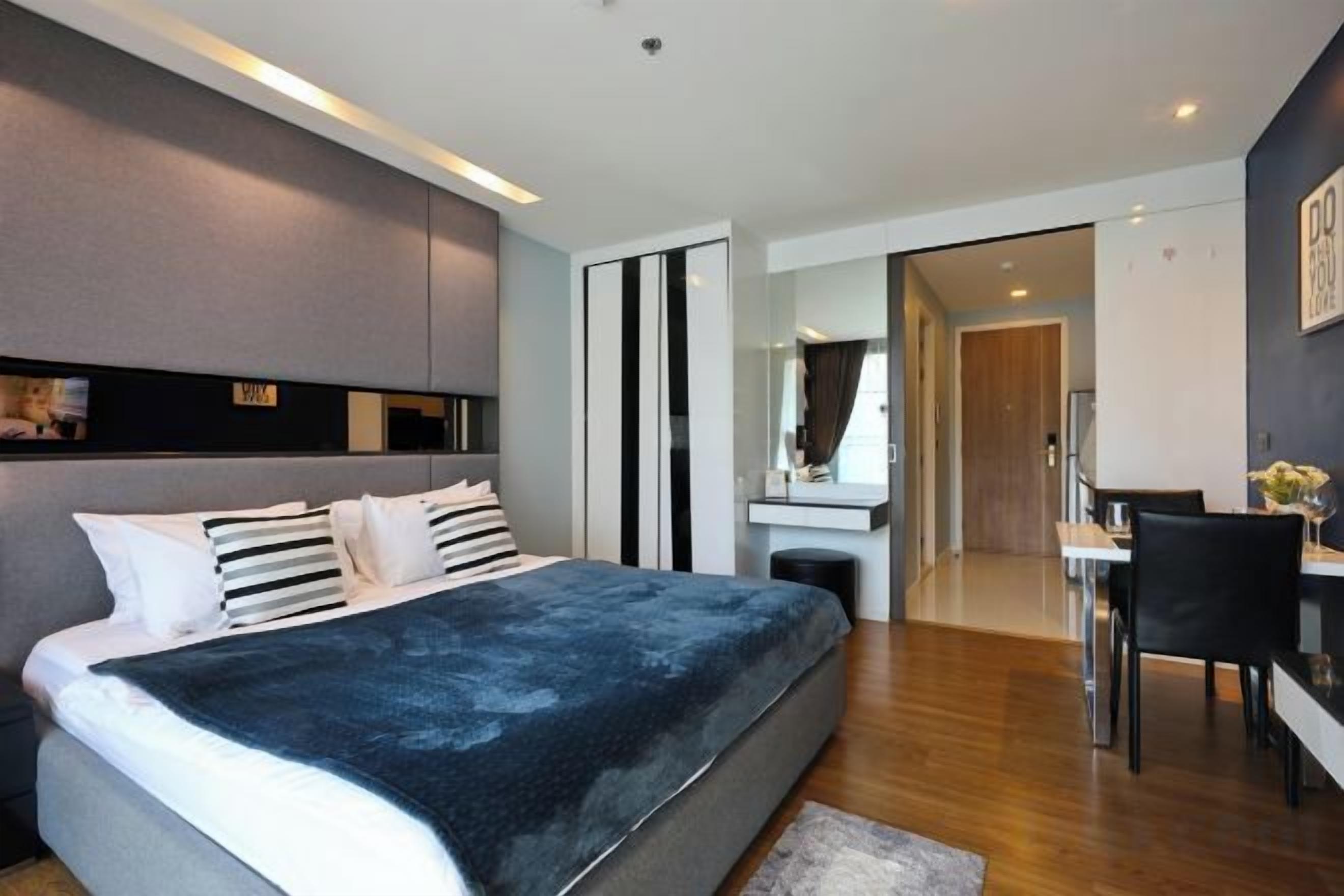 Un dormitorio moderno con una cama grande, mesitas de noche, un escritorio y un espejo.