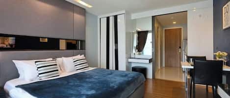 A modern bedroom with a large bed, bedside tables, a desk, and a mirror.