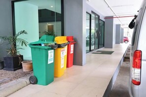 Un couloir avec trois poubelles, une plante en pot et un extincteur.