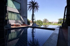 A swimming pool with lounge chairs, a palm tree, and a view of the surrounding landscape. - Vacation Home Rental The Starhillcondo Chiang Mai (Chiang Mai)