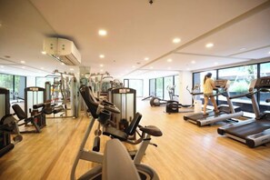 Una palestra con diverse attrezzature per esercizi, ampie finestre e un pavimento in legno.