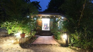 A pathway leading to a covered entrance with steps, surrounded by potted plants and illuminated by hanging lights. - Mridu Kishore Resort (Bichhiya)