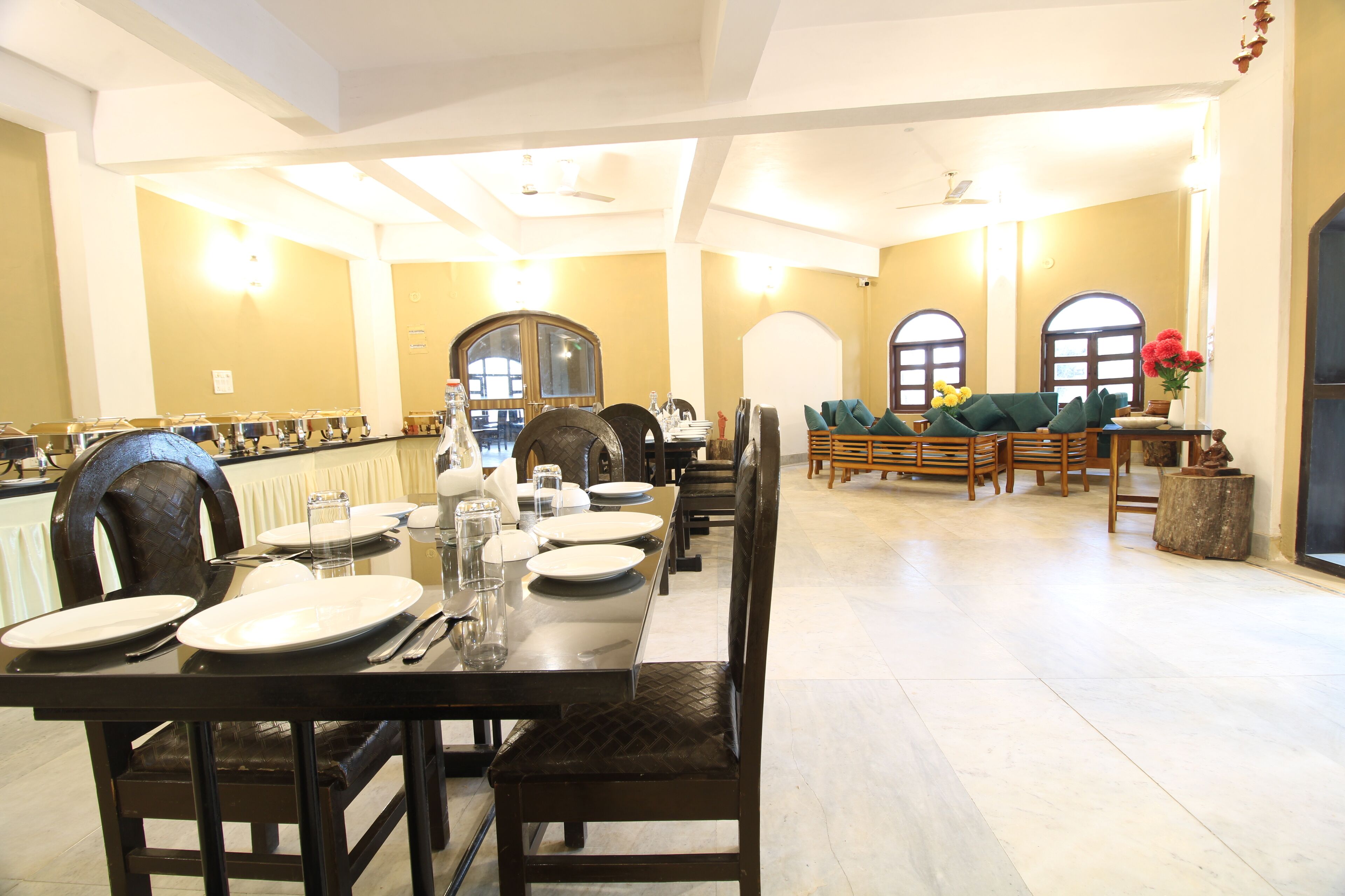 A dining area with a long table set for multiple people, chairs, and a buffet line.