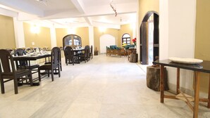 A spacious dining area with multiple tables and chairs, a large mirror, and a chandelier. - Mridu Kishore Resort (Bichhiya)