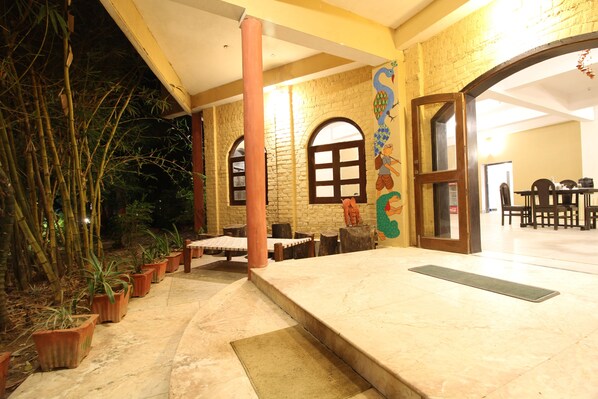 A courtyard with potted plants, a tiled floor, and a brick wall with a mural.