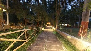A stone pathway leading to a gazebo, surrounded by trees and a bamboo fence. - Mridu Kishore Resort (Bichhiya)