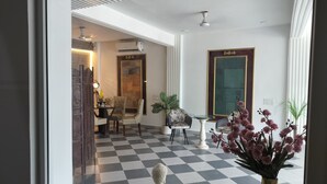 A hotel lobby with a checkered floor, a Buddha statue, and a large mirror. - Saffron Inn  (Greater Noida)