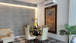 A dining area with a checkered floor, a glass table, and four chairs. - Saffron Inn  (Greater Noida)