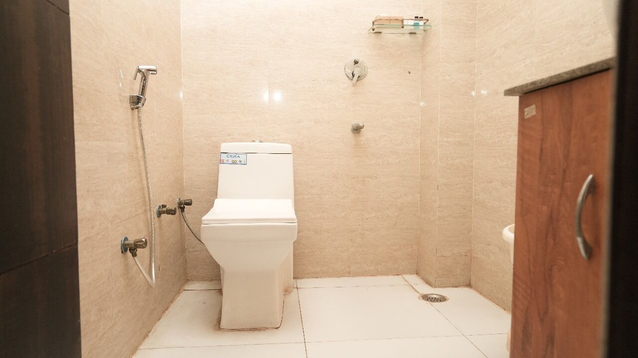 Et badeværelse med toilet, bruser og skab.