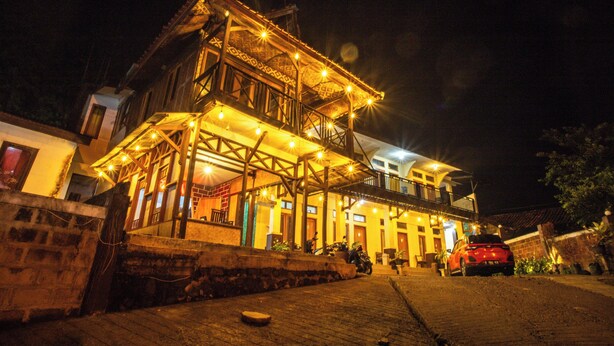 A two-story building with a balcony and outdoor seating area, illuminated by string lights. - ARBA Artana & Chipsari Hotel Pangalengan (Pangalengan)