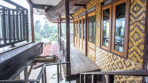 A wooden staircase leading to a covered outdoor area with a patterned wall and large windows. - ARBA Artana & Chipsari Hotel Pangalengan (Pangalengan)