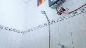 A bathroom with a toilet, a shower, and a wall-mounted electrical box. - ARBA Artana & Chipsari Hotel Pangalengan (Pangalengan)
