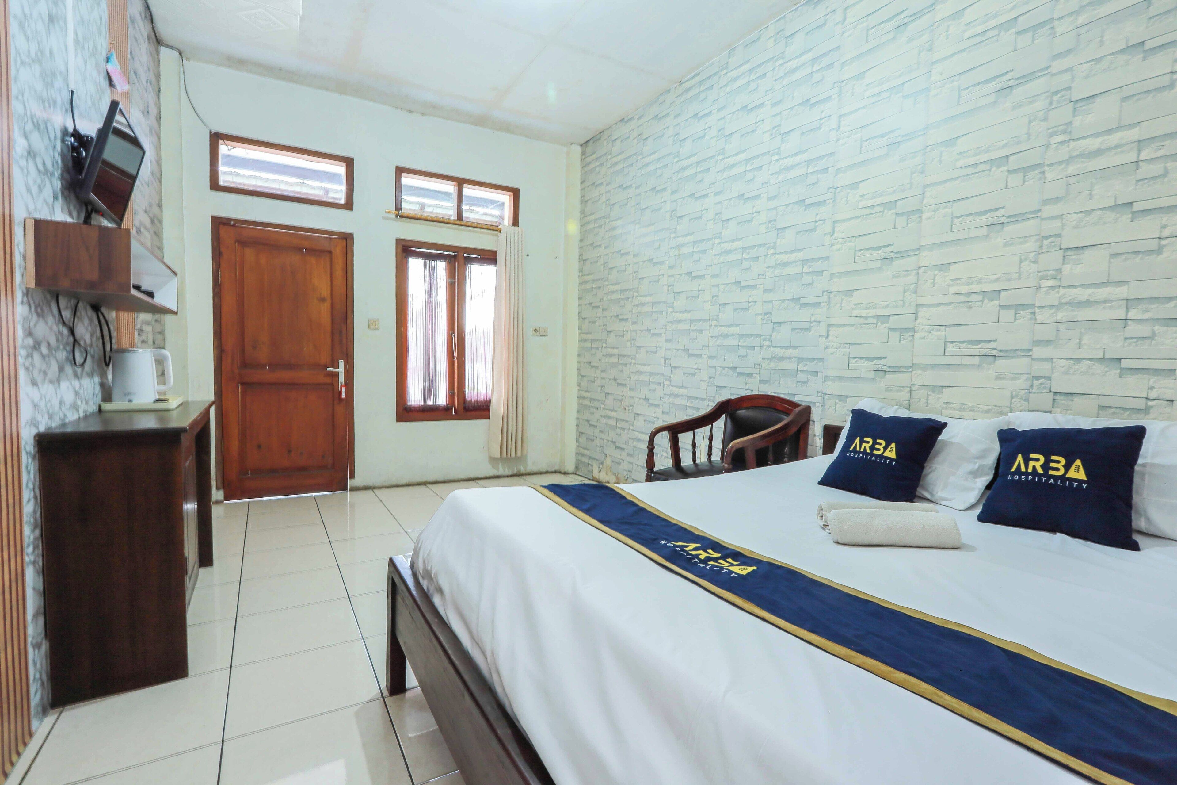 A hotel room with a bed, wooden furniture, a marble wall, and a stone-textured wall.
