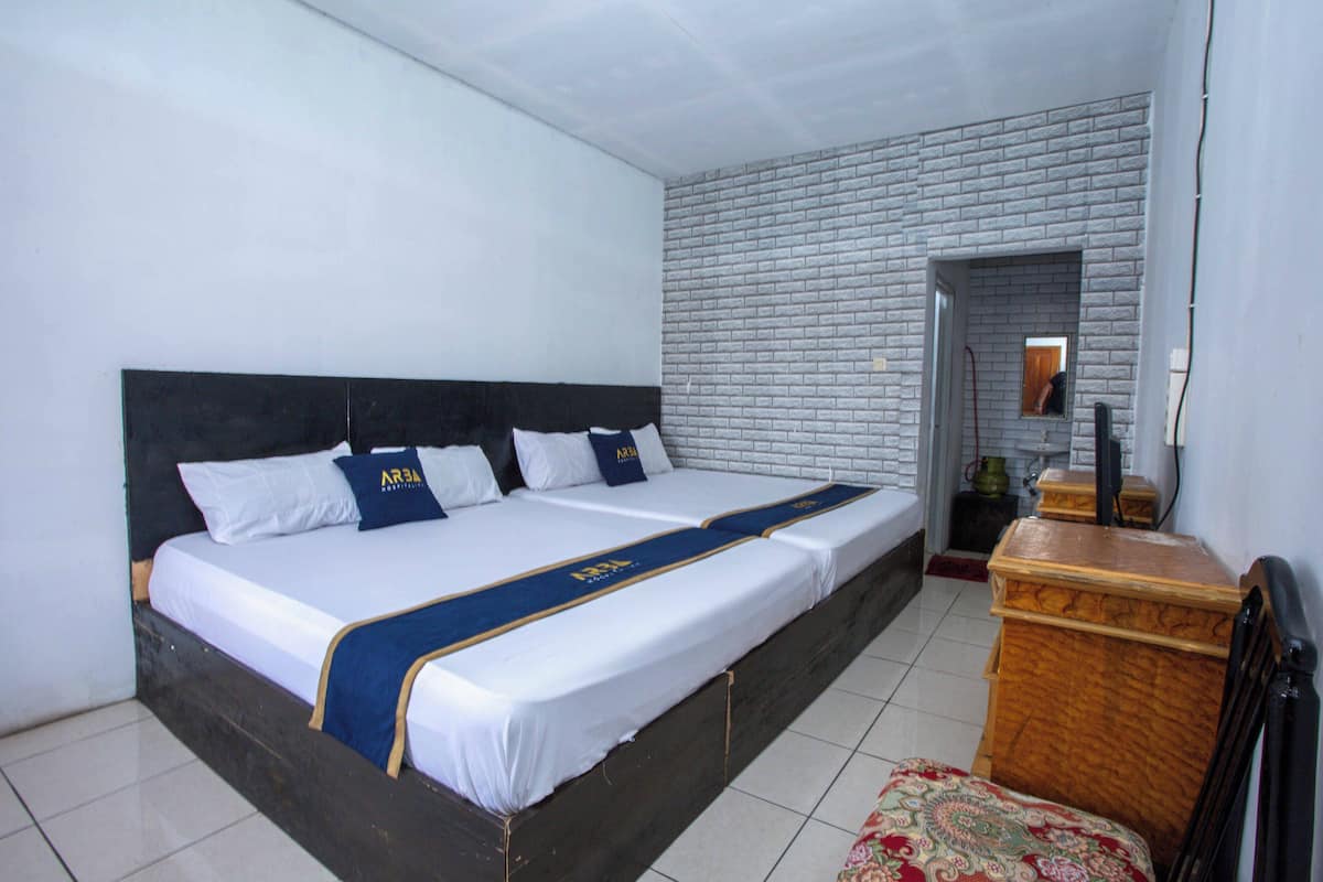 Une chambre d’hôtel avec un grand lit, une commode en bois et un mur décoré d’un motif en briques.