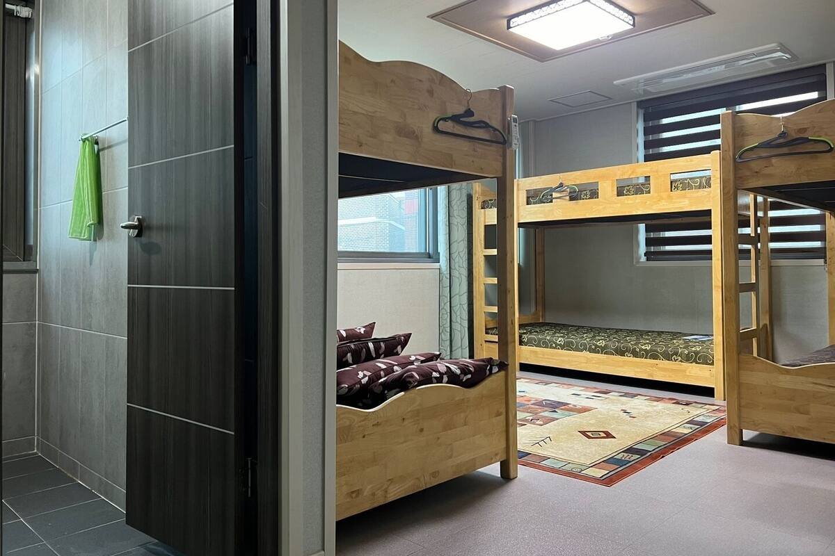 A room with a bunk bed, a wooden wardrobe, and a green towel hanging on the door.