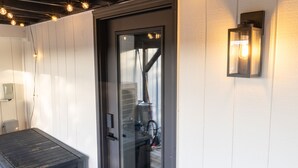 A modern entrance with a glass door, a welcome mat, and string lights above. - Charming Madrona Stay • Walk to Lake & Cafes, Shops, A/C • Parking (Seattle)