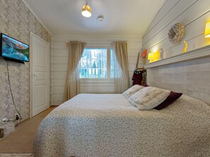 A bedroom with a bed, a television, a window with curtains, and a wall-mounted lamp. - Rehviranta by Interhome (Kuopio)